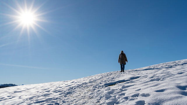 A woman takes a leisurely december stroll through the snow in the mountains, here on the Raten-Gottschalkenberg in the canton of Zug, Switzerland.