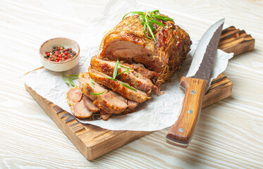 Rolled turkey roasted with spices and herbs on baking paper with knife and wooden white background...