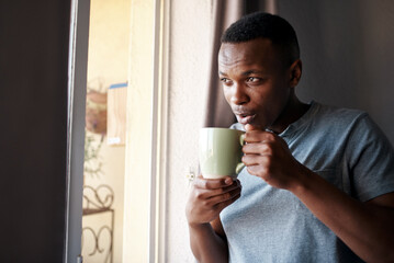 Coffee, morning and black man in window in home with drink, caffeine beverage and cappuccino for aroma. Happy, thinking and person with mug in living room for breakfast, relaxing and wellness