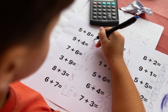 Over the shoulder view of a child who has dyslexia and dyscalculia doing math homework.