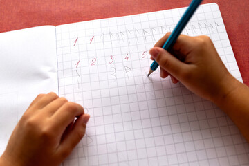Child's hands writing numbers in a notebook. The problem of dysgraphia and dyscalculia.