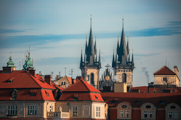 Fototapeta premium Gothic spires of Prague rise above red rooftops on a clear day, showcasing the city's historic architecture and charm