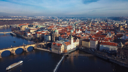 Aerial view of Prague showcasing historic architecture and the Vltava River under a clear blue sky in early afternoon light