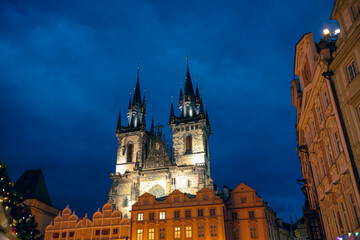 Fototapeta premium Twilight in Prague with gothic architecture and illuminated spires against a blue sky at night