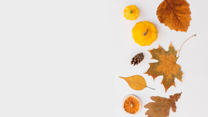 Autumn holiday frame composition with pattern made of leaf, punpkins, dried orange, pine cone on...