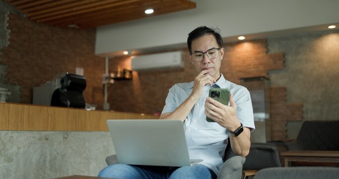 Businessman chatting on laptop. communication technology. Asian Middle-aged man using smartphone to shop online. Senior make financial transactions, transfer money via bank apps, order products.