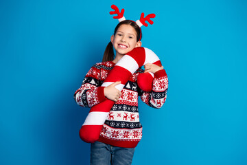 Photo of lovely cute girl wear red sweater christmas theme party hold big toy sweet candy event isolated on blue color background