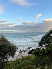 Surfers on a beach with boards, ocean waves in background