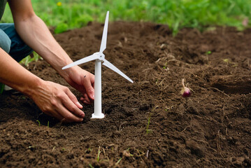 mani di uomo piantano piccola pala eolica nel terreno. energia sostenibile