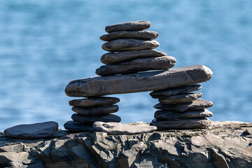 Inukshuk is a stack of granite rocks in the form of a person. The formation is a symbol of direction. The Inuit traditional figure is high on a hill. The background is a blue sky with some clouds.