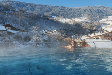 A woman relaxes in swimming pool in winter season. Winter resort for winter holiday - vacation.