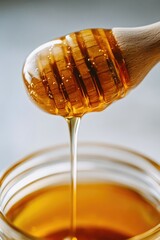 Drizzling Organic Honey from a Dipper into a Clear Jar
