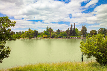 Visitors enjoy the serene atmosphere of the lake in Parque General San Martin, surrounded by vibrant trees, perfect for relaxation and leisure activities.