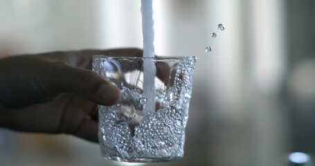 Hand pouring water into glass in slow-motion at 800 fps, highlighting detailed water flow and bubbles, representing purity and refreshment in an everyday scene