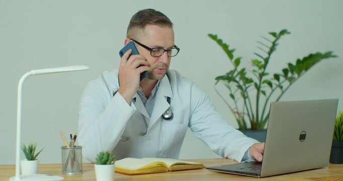 Male Doctor Does Call Consultation, While Sitting in His Office.