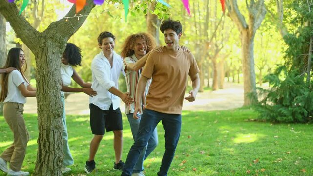 Friends playing conga line around tree at birthday party