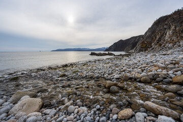 The coast of the Sea of ​​Okhotsk, Magadan Region, Russia. View of the rocky seashore. In the foreground is the mouth of the Kongali Creek. In the distance are capes. Nature of the Russian Far East.