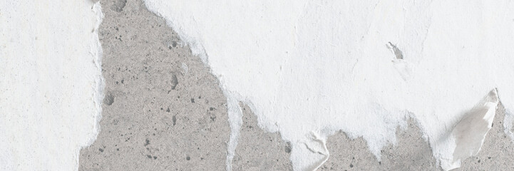 Torn old faded paper wallpaper on a concrete wall. Ragged scraps of white paper on a gray background. Vintage texture for background and design. Closeup view with copy space for text. High resolution.