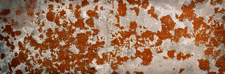 Peeling paint on the wall. Panorama of a concrete wall with old cracked flaking paint. Weathered rough painted surface with patterns of cracks and peeling. Wide panoramic grunge texture for background