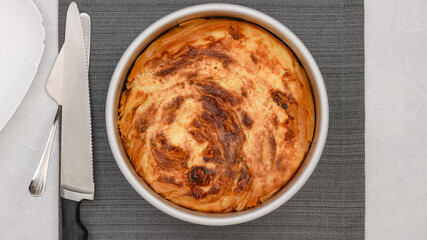 Freshly baked phyllo dough pie with a golden crust close-up on a kitchen table, just out of the oven