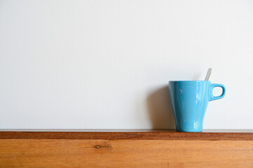 Blue coffee mug on wood table and white background with copy space. Selective focus on Coffee cup..