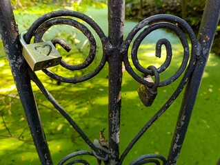 A heart shaped padlock attached to a wrought iron gate