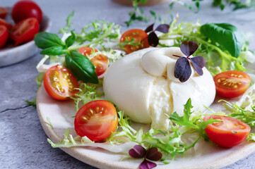 Creamy burrata cheese paired with basil leaves and tomatoes.