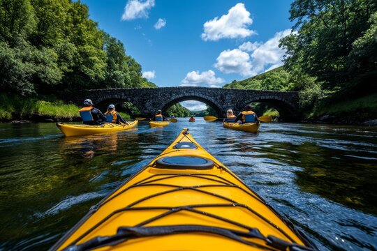 Kayakers paddling down the River Tavy, passing under a stone bridge