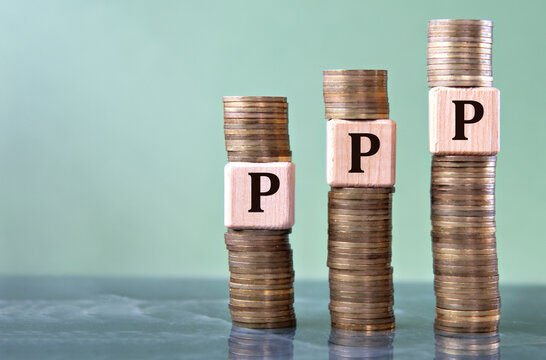 PPP - acronym on wooden cubes on stacks of coins
