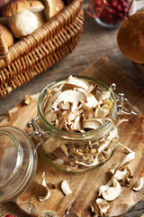 Dried wild king bolete or porcini mushrooms in a jar on a table in autumn