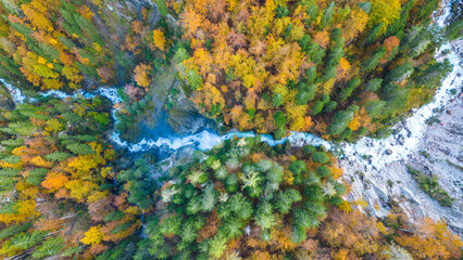 A stunning aerial capture of Martuljek Lower Waterfall in the autumn season, surrounded by vibrant fall foliage in the Slovenian Alps