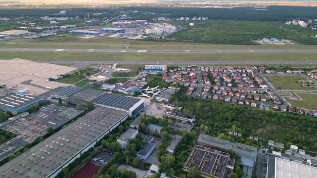 Aerial footage of Bucharest international airport aurel vlaicu on a summer afternoon. Helicopter footage of landing strip, airplanes, hangars and infrastructure surrounding the airfield. 
