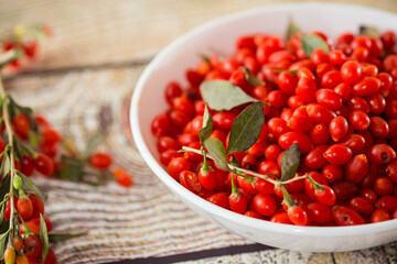 fresh ripe red goji berries in a bowl on a wooden table
