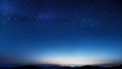 Fototapeta premium Expansive Night Sky Over Mountainous Horizon with Thousands of Stars Illuminating the Deep Blue Twilight, Capturing the Serene Transition from Dusk to Dawn in a Vast and Tranquil Wilderness