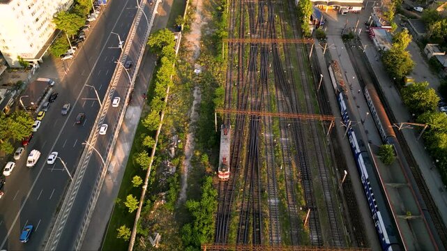 High angle drone footage of the central train station in Bucharest, Romania. Locomotives, rails and wagons seen from above on a summer sunny afternoon. Top down shot of colorful trainyard.
