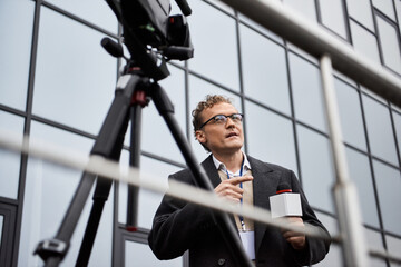 A professional journalist in glasses engages with a microphone, capturing news on location.
