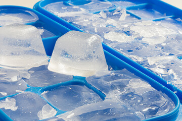 A close up image of several cracked and broken ice cubes in a blue ice cube tray. 
