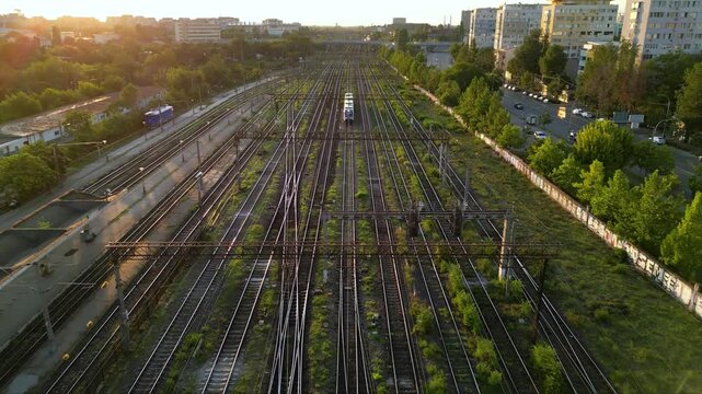 High angle drone footage of the central train station in Bucharest, Romania. Locomotives, rails and wagons seen from above on a summer sunny afternoon. Top down shot of colorful trainyard.
