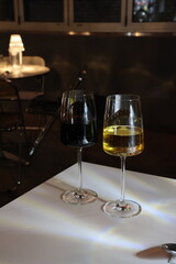 Two wine glasses, one red and one white, sit on a table