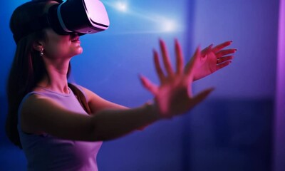Woman experiencing virtual reality with a VR headset, reaching out with her hand in an immersive digital world