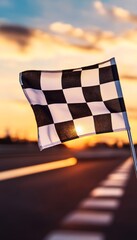 Checkered flag waving against a blurry race track and sunset marking the finish line and victory.