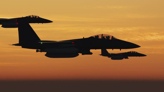 Three tactical twin jet engine fighter aircraft on a combat mission. Modern war jet airplanes flying in formation. Military planes silhouette against sunset. Sound barrier speed, air to air.
