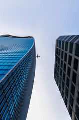 Stunning view from below of a skyscraper and another one next to it with the clear blue sky...