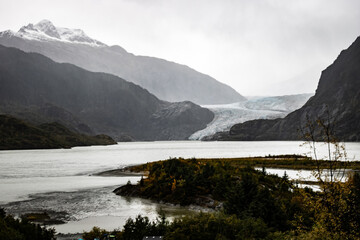 Long view of Glacier cascading down the mountains, including a foreground water element curving through the mountainous terrain.