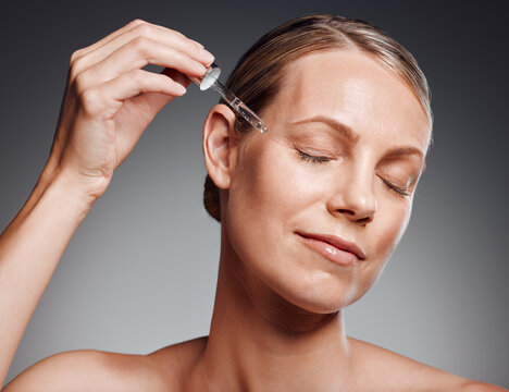 Mature woman, serum and anti aging for cosmetics, glow and dermatology on studio background. Female person, hyaluronic acid and treatment with cosmetology, beauty and eyes closed for skincare product