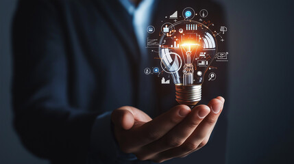 Businessman holding creative light bulb with growth graph, analytics icons. Utilizing analytics technology to develop new strategies and insights that enhance successful performance in global business