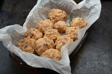 Semi-finished products, raw meatballs, meat patties on a parchment on a black table