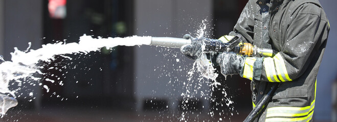firefighter is spraying foam extinguishing agent with a powerful hose to control a fire