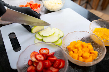 Close-up of a woman's hands chopping apple and other fruits to prepare a nutritious breakfast