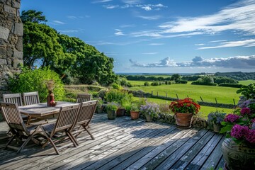 Fototapeta premium Beautiful Garden with Wooden Furniture on Deck Overlooking Green Field and Country House in Guernsey Style